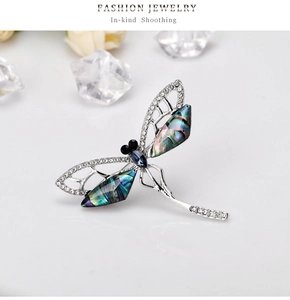 Macro shot of vintage dragonfly brooch with iridescent abalone shell wings and blue crystal