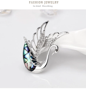 Détail de la broche cygne élégante avec texture coquillage et ailes en cristal brillant