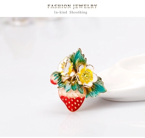 Vue macro d'une broche fraise émaillée colorée avec feuilles vertes et fleurs blanches