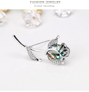 Détail macro d'une broche rose argentée avec cœur en nacre et pétales en cristal