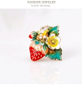 Détail de la broche fraise en émail rouge avec feuilles vertes et fleurs en cristal
