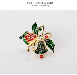 Macro shot of Christmas bell brooch with red and green rhinestones and golden bow