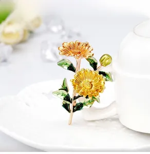 Dettaglio macro della spilla a margherita in smalto con petali gialli e foglie verdi