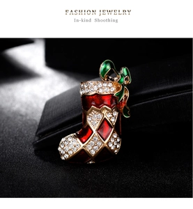 Détail de la broche botte de Noël avec émail rouge, nœud vert et cristaux blancs