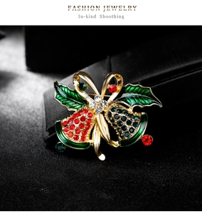 Macro shot of Christmas bell brooch with red and green rhinestones and golden bow