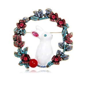 Macro detail of white enamel bunny brooch with red and blue rhinestones on gold floral wreath