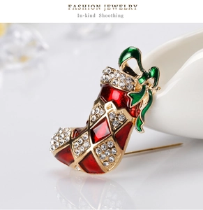 Vue détaillée d'une broche botte de Noël en émail rouge ornée de strass brillants