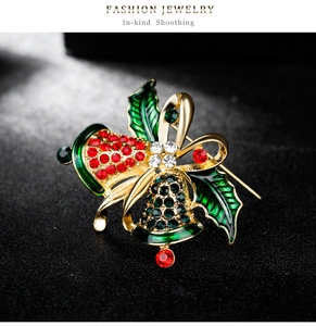 Close-up of vintage Christmas bell brooch with red rhinestones and green holly leaves