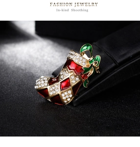 Détail macro d'une broche botte de Noël en strass avec émail rouge et nœud papillon vert