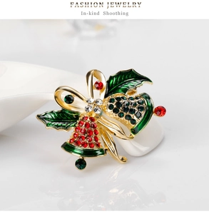 Detailed close-up of Christmas bell brooch with red and green rhinestones and golden bow
