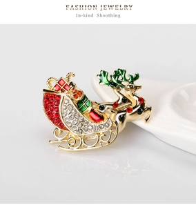 Detailed close-up of a festive reindeer sleigh brooch with red and white rhinestones