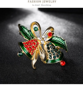 Macro shot of vintage Christmas bell brooch with red and green rhinestones on gold base