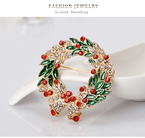 Detail of Christmas wreath brooch with red rhinestones and green enamel leaves