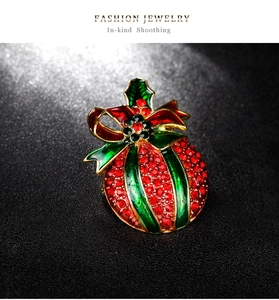 Close-up of Christmas brooch with red rhinestones, green holly leaves and enamel finish