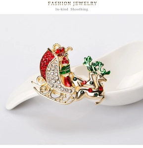 Detail of Christmas Santa sleigh brooch with red and green rhinestones on gold base