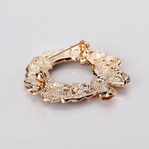 Achteraanzicht van gouden kerstkrans broche met sierspeldsluiting en kleurrijke strassteen