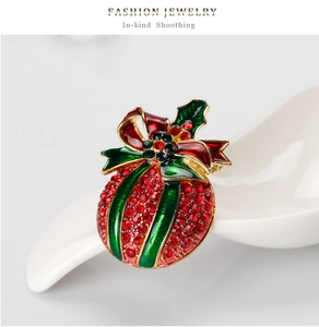 Macro shot of a Christmas gift bag brooch with red and green rhinestones and enamel leaves