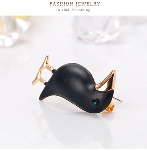 Macro detail of black enamel raven brooch with gold beak and green rhinestone eye