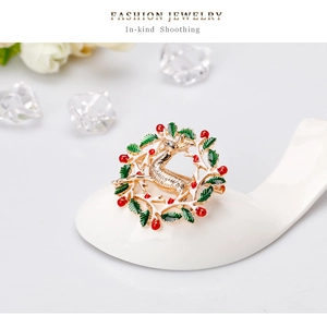 Détail d'une broche renne de Noël avec perles rouges et feuilles en émail vert