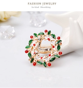 Détail de la broche renne de Noël avec couronne d'émail vert et touches de baies rouges