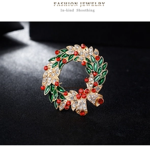 Close-up of Christmas wreath brooch with red rhinestones and green enamel leaves