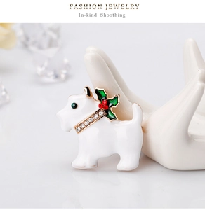 Détail macro d'une broche chien en émail blanc avec collier brillant et houx