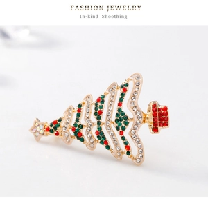 Dettaglio di una spilla a forma di albero di Natale dorata con strass colorati e stella