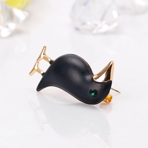 Creative matte black kiwi bird brooch with golden beak and green crystal eye on white surface
