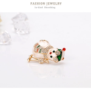 Detail of a skiing snowman brooch with sparkling crystals and green enamel on a metal base