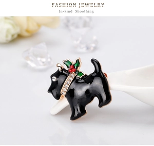 Vue macro d'une broche chien en émail avec feuilles de houx et pierres de zircon