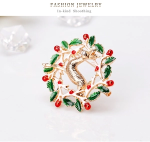Détail de la broche renne de Noël avec couronne en émail vert et baies rouges