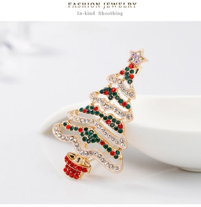 Dettaglio di una spilla a forma di albero di Natale con strass colorati su lega dorata lucida