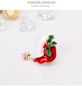 Macro detail of Christmas hat brooch with red enamel, holly leaves and gold star charm