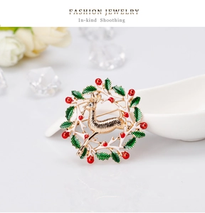 Détail d'une broche couronne de Noël colorée avec un renne doré et des baies rouges