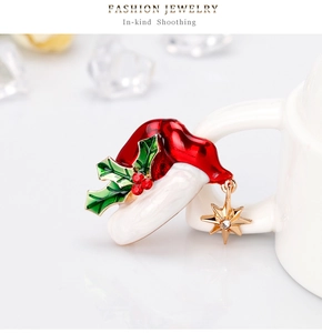 Macro shot of a Christmas hat brooch with holly leaf and gold star hanging on a cup