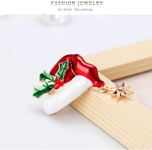 Macro detail of Christmas hat brooch with holly leaves and gold star pendant