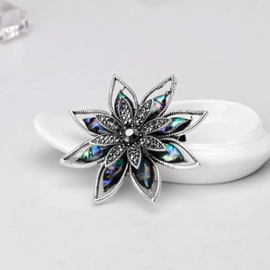 Dettaglio ravvicinato della spilla a fiore argento vintage con abalone e pietre nere