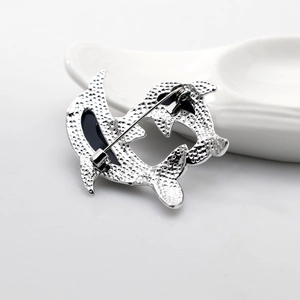 Macro detail of silver alloy dolphin brooch back showing safety pin clasp and texture