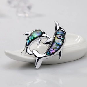 Macro detail of silver dolphin brooch featuring iridescent natural abalone shell inlay