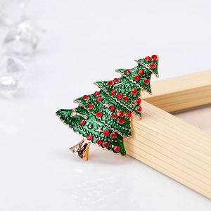Detail der Weihnachtsbaum-Brosche mit grüner Emaille und roten Steinen auf Holzhintergrund