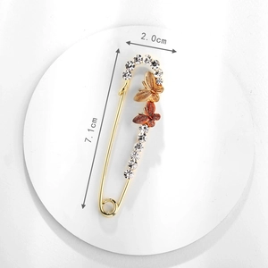 Dettaglio di una spilla a farfalla dorata da 7,1cm con strass e misure indicate
