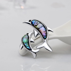 Close-up of double dolphin brooch with iridescent abalone shell inlay on silver metal