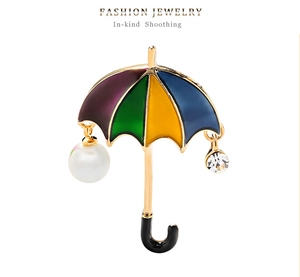 Detailed close-up of umbrella brooch with colorful enamel, pearls and rhinestones