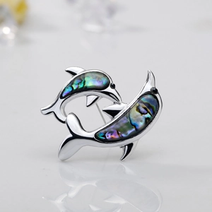 Macro view of twin dolphins brooch with iridescent abalone shell and silver metal finish