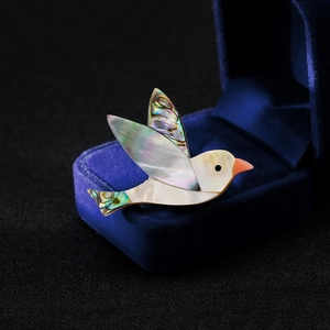 Vue macro d'une broche oiseau en nacre d'abalone naturelle et nacre blanche