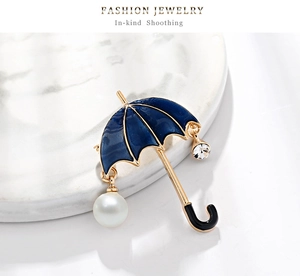 Macro shot of blue enamel umbrella brooch with pearl drop and crystal details