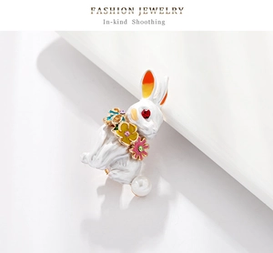 Detail of white enamel rabbit brooch with floral accents and a faux pearl tail