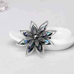Elegante spilla floreale in argento con petali di conchiglia e cristalli neri lucidi