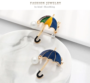 Macro view of umbrella brooch with colorful enamel, sparkling crystals and pearls