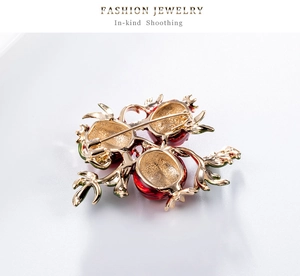 Detailed back view of a pomegranate brooch showing the safety pin clasp and gold alloy finish